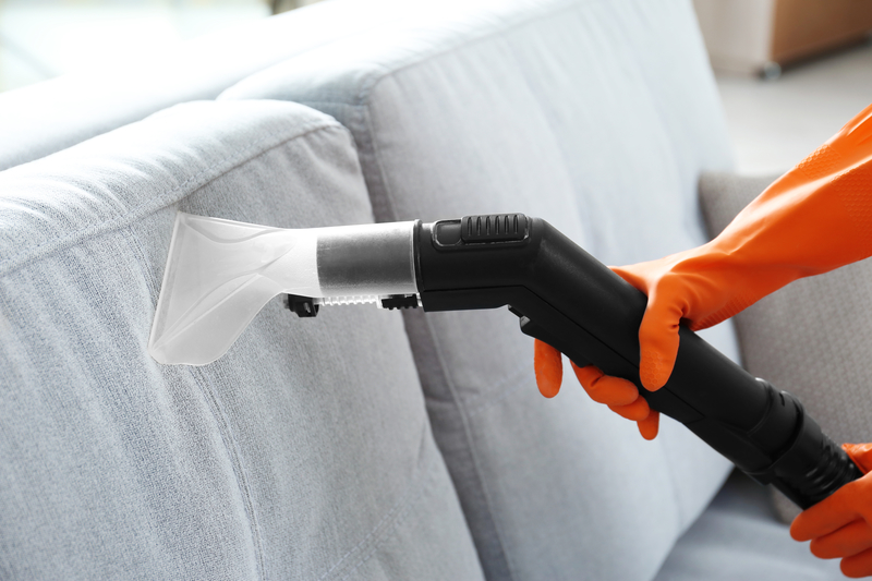 Female hands cleaning couch with vacuum cleaner, closeup cleaning couch with vacuum cleaner
